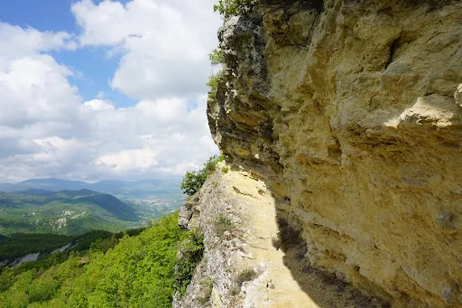 Sentiero roccioso su scogliera con vista sulla valle